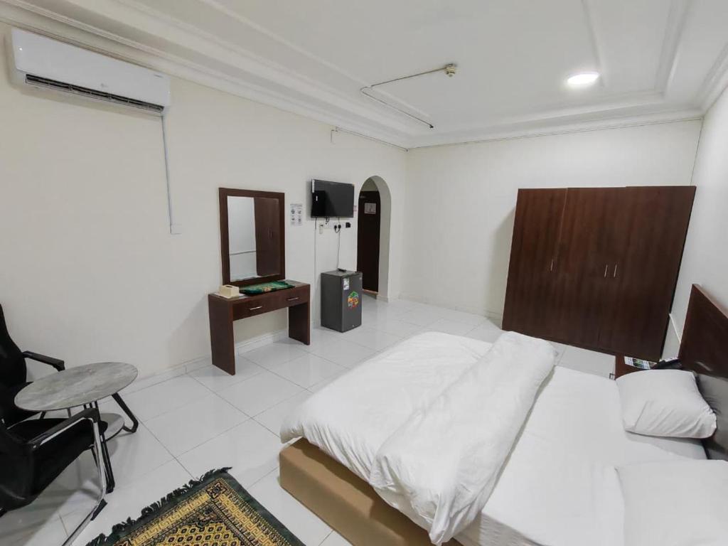 a bedroom with a bed and a desk and a chair at فندق فاديه الذهبي in ‘Ushayrah