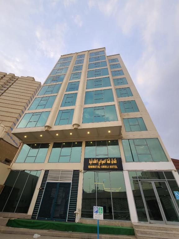 a tall building with a sign in front of it at Qimmat AlAwali Hotel in Az Zahrāʼ