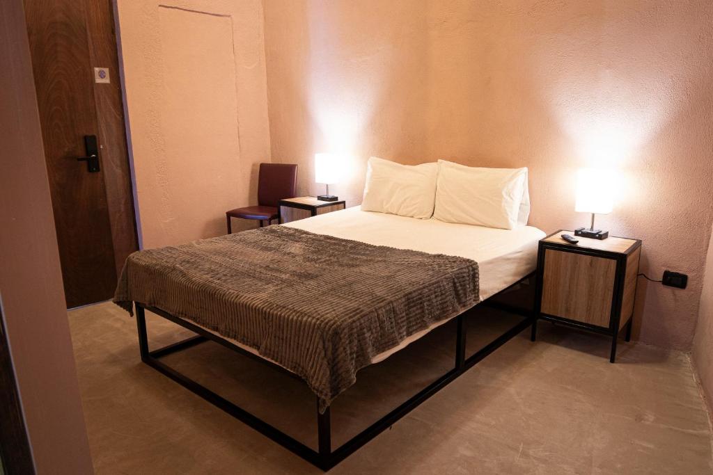 a bedroom with a bed with two lamps on two tables at Capital O Adhoc Barrio Antiguo in Monterrey