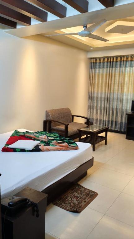 ein Zimmer mit einem Bett, einem Stuhl und einem Tisch in der Unterkunft Well Park Resort in Cox's Bazar