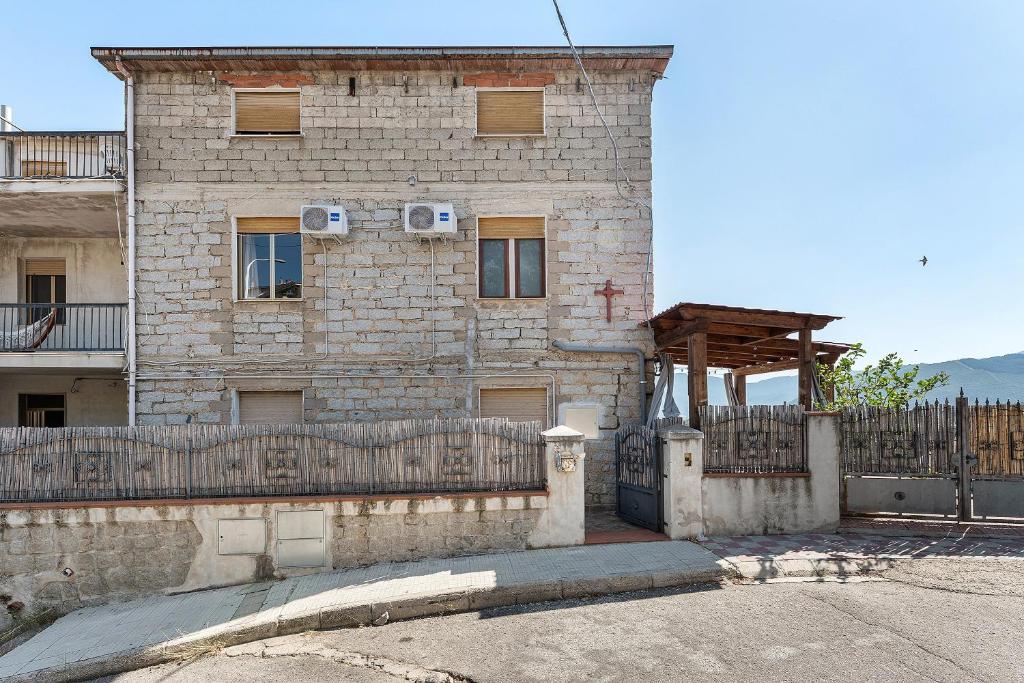 a brick building with a fence in front of it at Ammentos La Casa di Rosa in Orgosolo