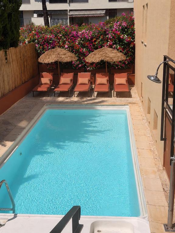 a large swimming pool with chairs and umbrellas at Hôtel Gallia Cannes in Cannes