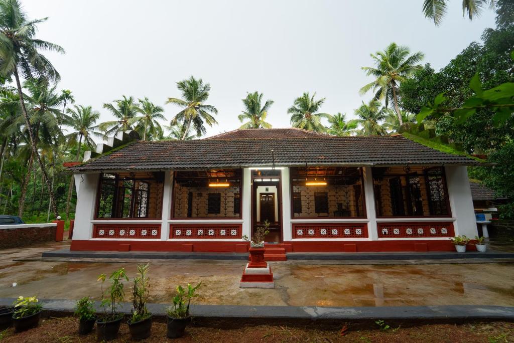 a small building with palm trees in the background at Chandralayam Heritage Homestay in Bekal