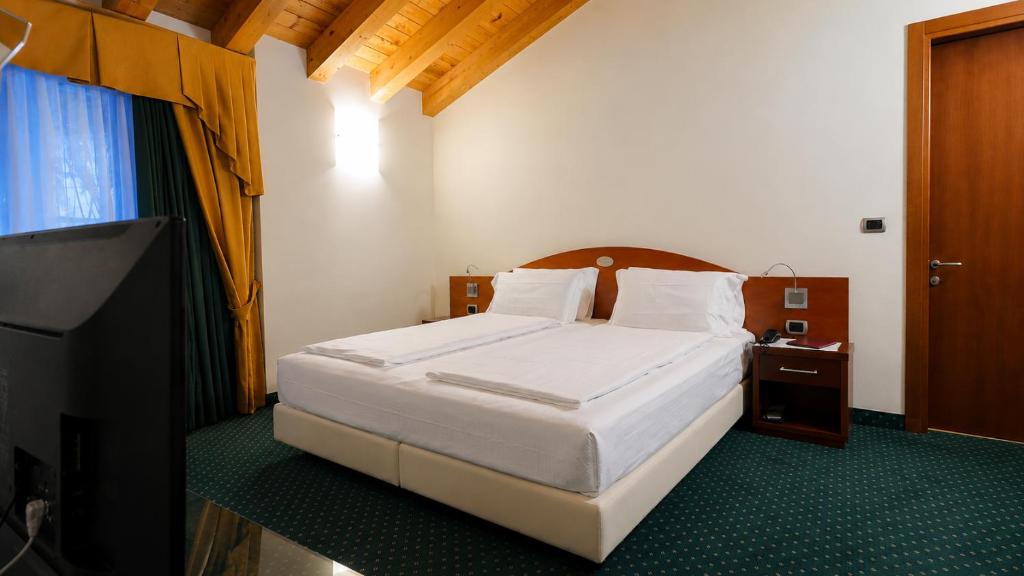 a bedroom with a bed and a flat screen tv at Hotel Capri Bardolino 3S in Bardolino