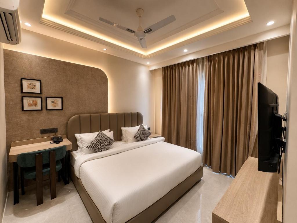 a bedroom with a bed and a desk and a television at Lime Tree Hotel Golf Course Road, Gurgaon in Gurgaon