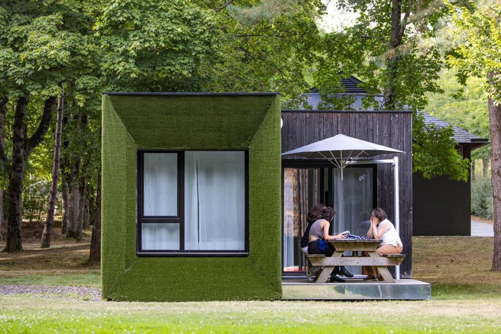 two women sitting at a picnic table in a green house at Camping des Gayeulles in Rennes