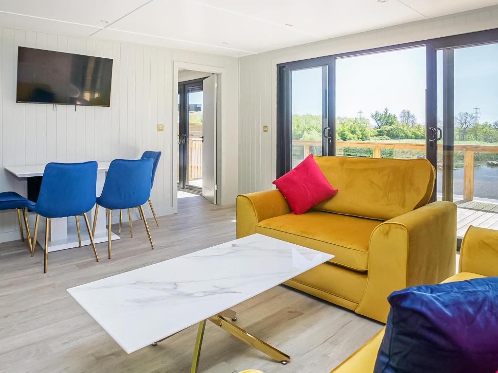 a living room with a yellow couch and blue chairs at Nightingale Lodge - Uk51938 in Yarm