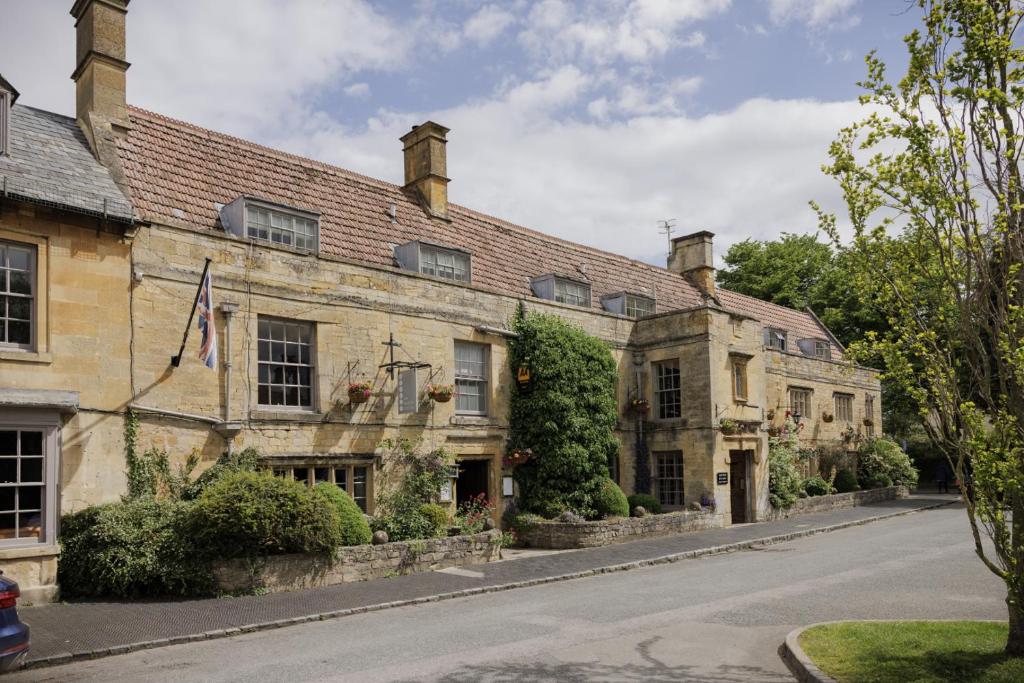 an old stone building with a flag on a street at The Manor House Hotel in Moreton in Marsh