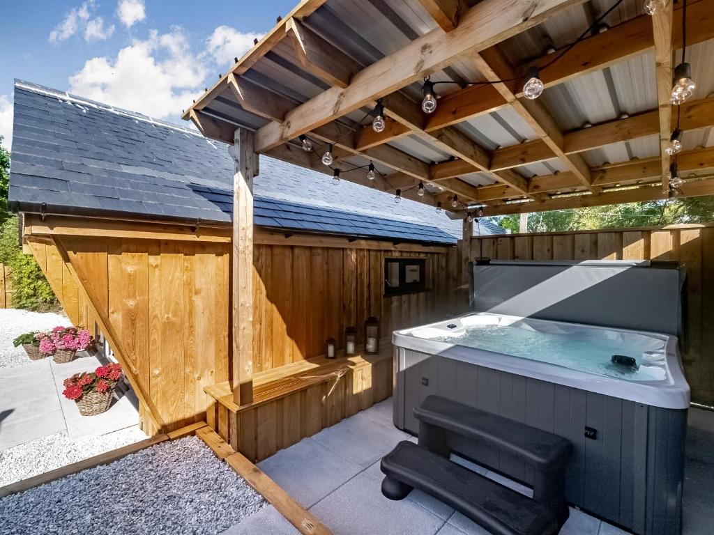 a hot tub in a patio with a wooden building at Olchard Lodge in Newton Abbot