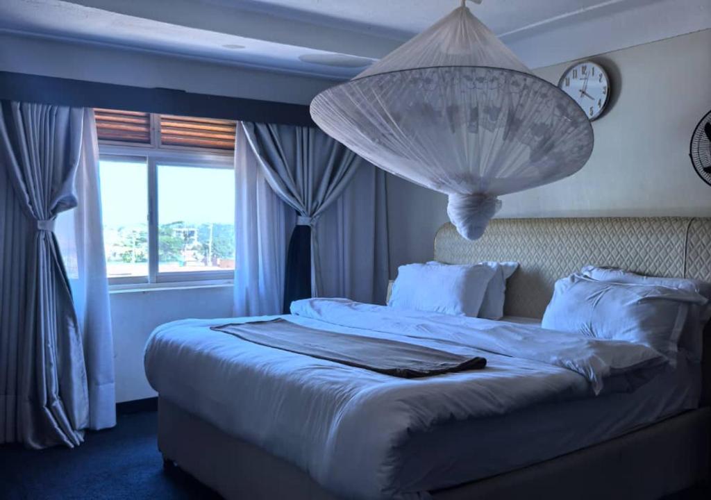 a bedroom with a large bed with a chandelier above it at Kaa Highway Hotel Mukono in Mukono