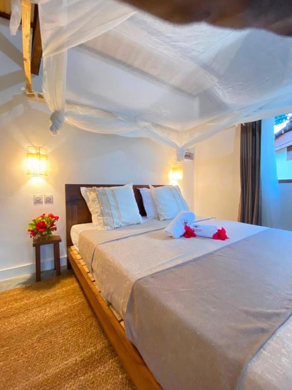 a bedroom with a large bed with red flowers on it at ANKAVIA Lodge in Toamasina
