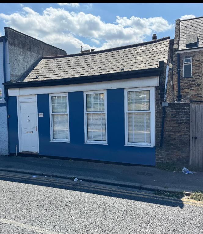 a blue house with a white door on a street at A cozy self-contained bungalow in Margate