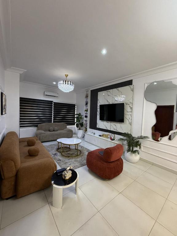 a living room with a couch and chairs and a tv at The Luxe Haven in Lekki Phase 1