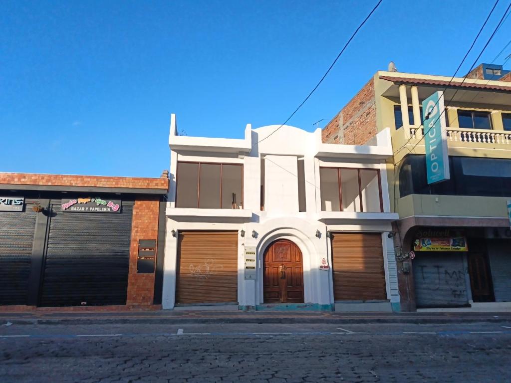 a white building with brown garage doors on a street at AylluWasi Guesthouse in Otavalo