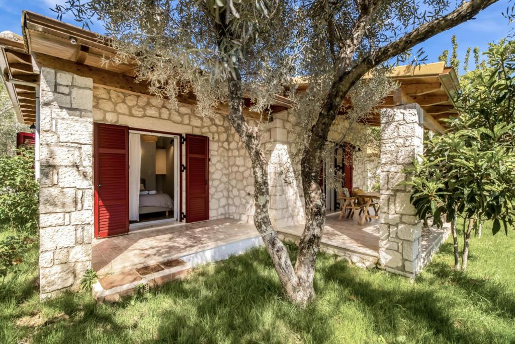 a stone house with red doors and a tree at Apanema Mindfulness, Relaxing Adults Only Resort, Fast WiFi, Pool, Sauna, Massage in Asprogerakata