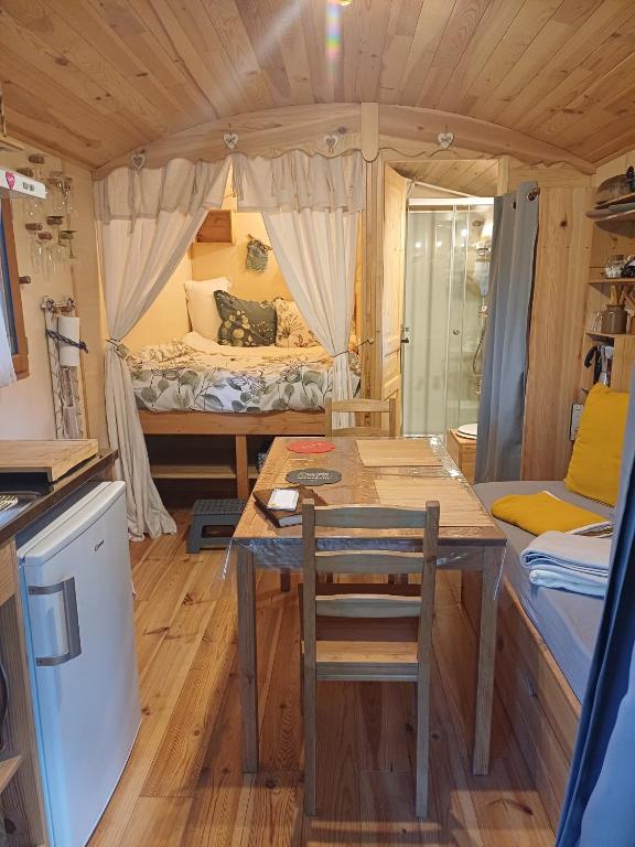 a small room with a table and a bed at Roulotte des 2M in Vildé-Guingalan