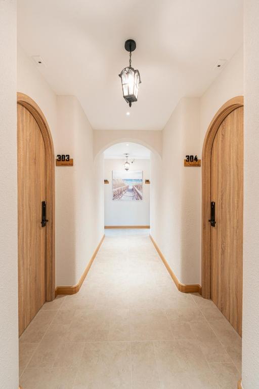 an empty hallway with wooden doors and a painting on the wall at Maison Thu in Phú Quốc