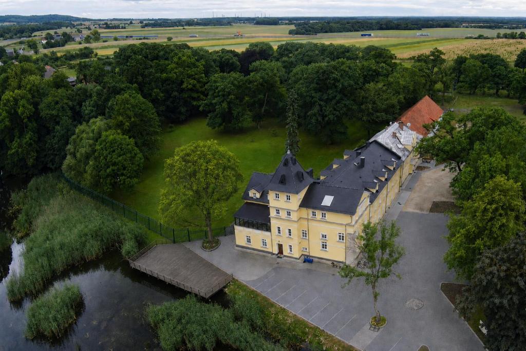 an aerial view of a large yellow house with a black roof at Rezydencja Pałac Lucja BB in Zakrzów