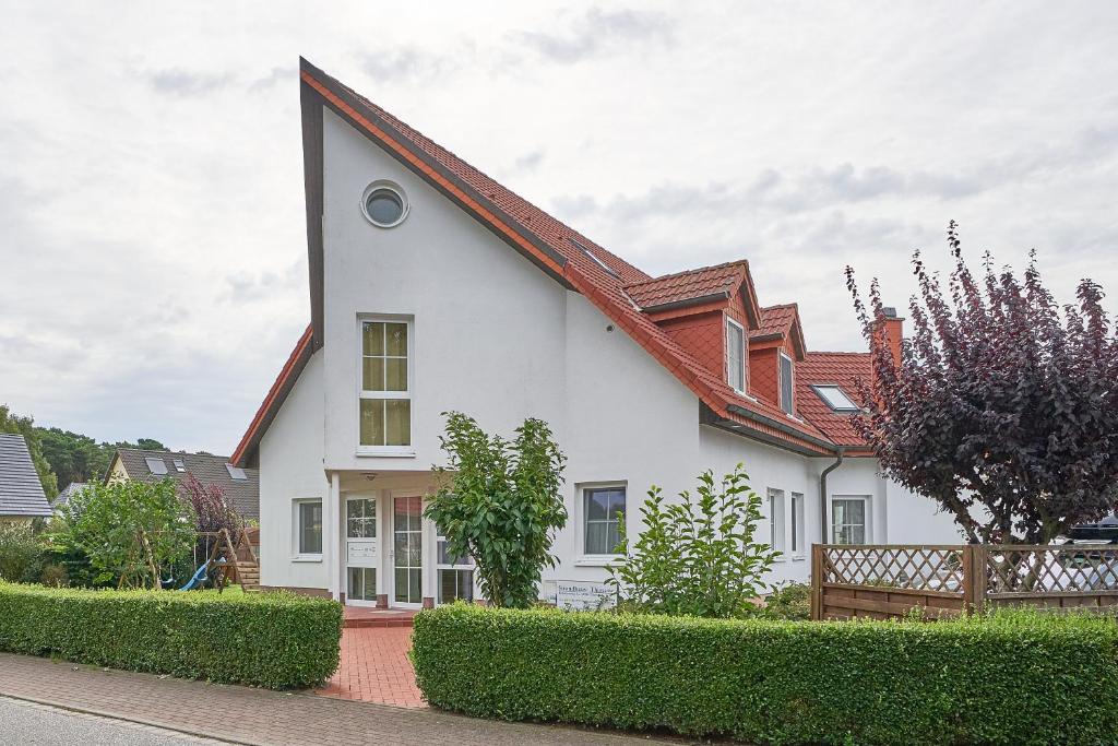 a white house with a red roof at Strandhaus Thiessow, Wohnung mit 2 Bädern in Thiessow