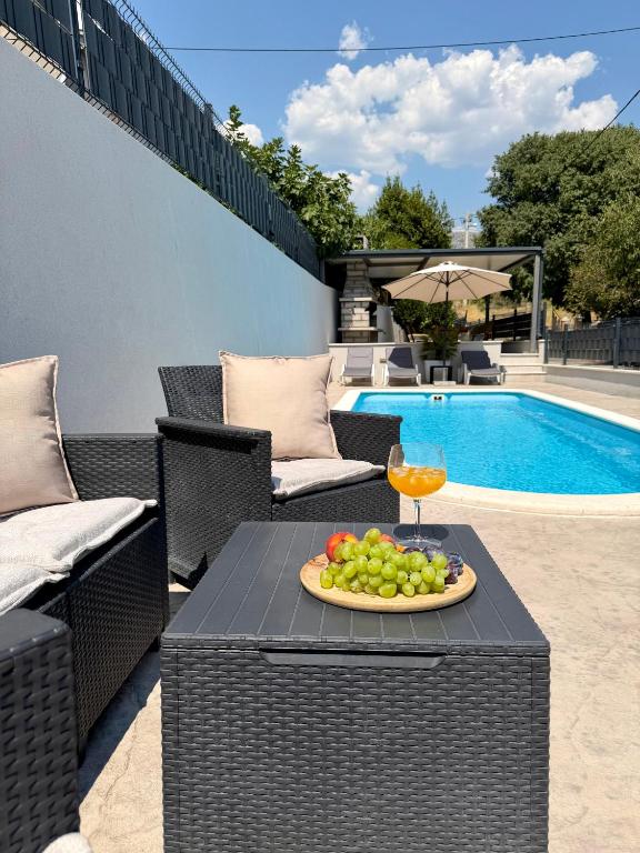 a plate of fruit on a table next to a pool at Apartments Antini in Solin