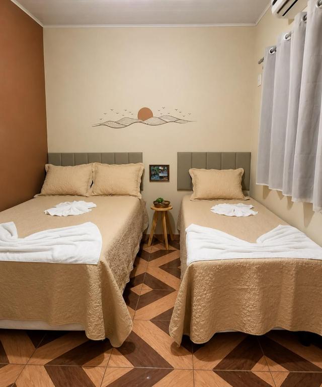 two beds sitting next to each other in a room at Sol do Jalapão Kitnets Completas com Ar a 6km do Aeroporto de Palmas in Palmas