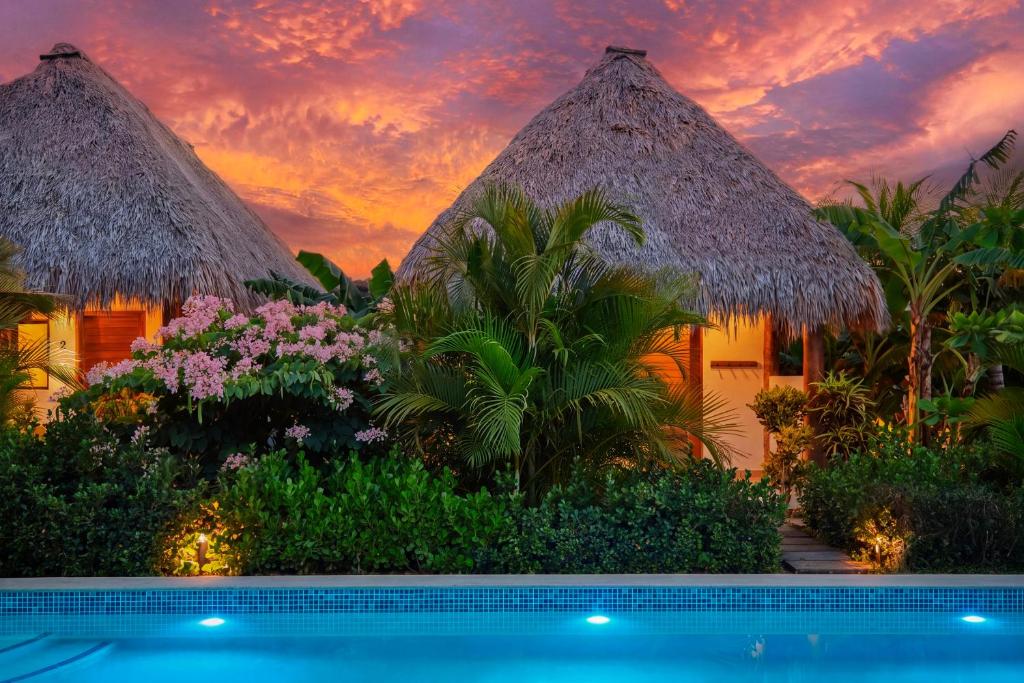 a villa with a swimming pool in front of a sunset at Banana Tree Popoyo in Popoyo