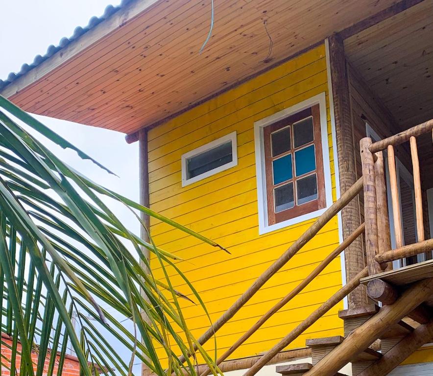 a yellow house with a window and a palm tree at Casa da Raposa in Iguaíba