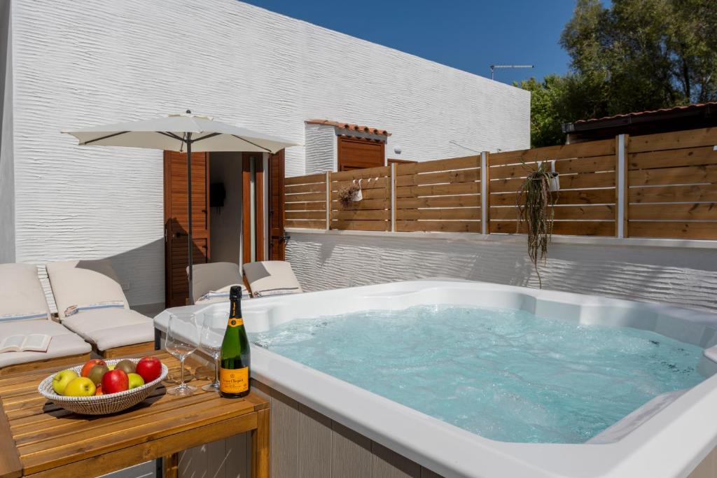 a hot tub with a bowl of fruit and a bottle of wine at AHR Residence Porto Pollo in Porto Pollo