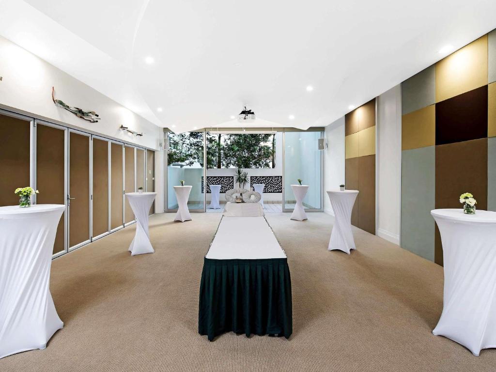a room with white tables and white chairs at The Sebel Maroochydore in Maroochydore