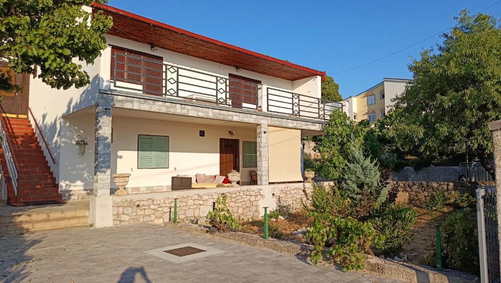 a white house with a balcony on a street at Olcsica Apartment in Klenovica