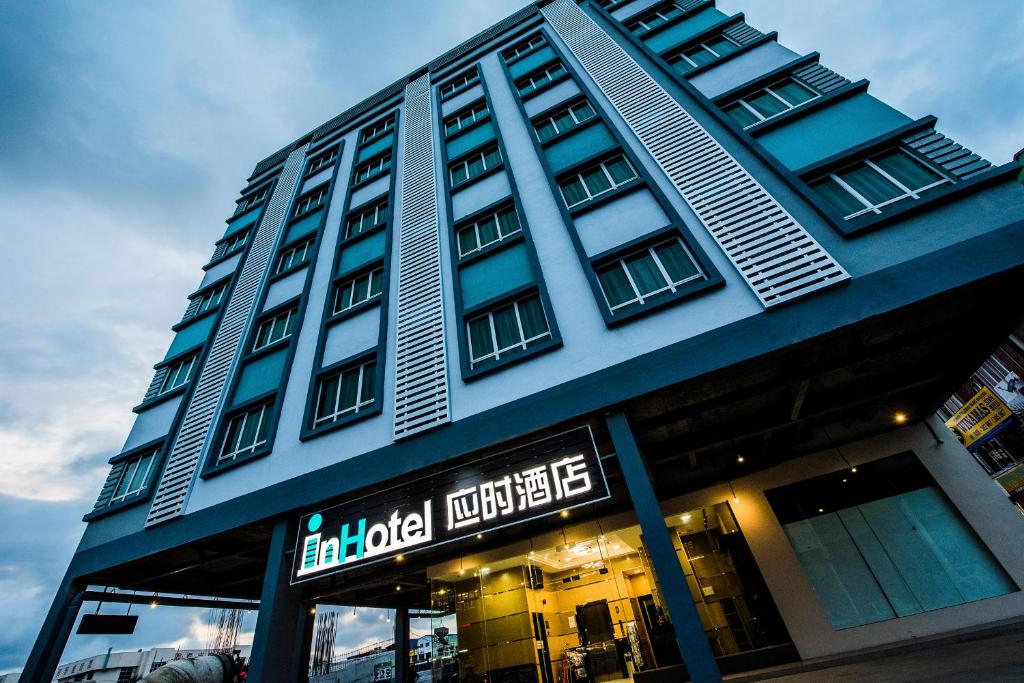 un grand bâtiment avec un panneau devant lui dans l'établissement inHotel Inanam, à Kota Kinabalu