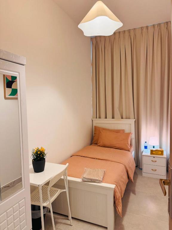 a small bedroom with a bed and a table at Majestic Inn in Abu Dhabi