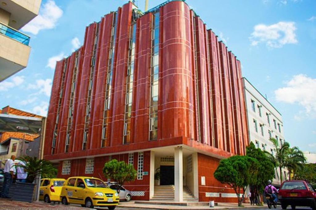 a red building with cars parked in front of it at Hotel Macedonia Plaza Itagui in Medellín