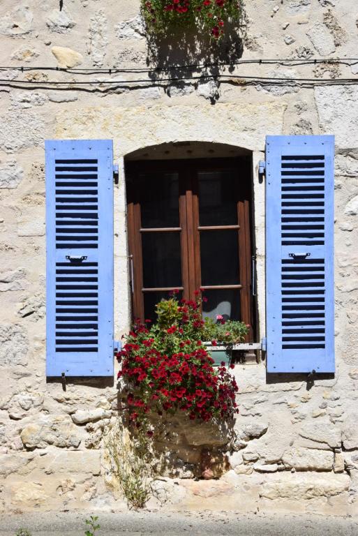 a window with blue shutters on a stone building with flowers at La Maison bleue in Rossillon