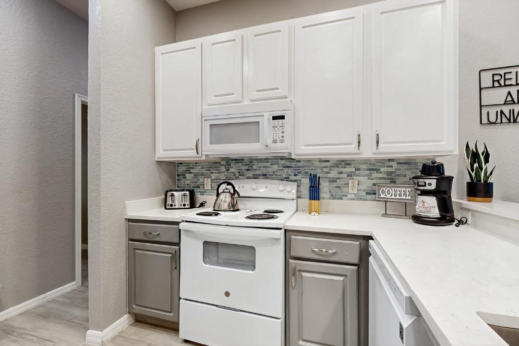a kitchen with white cabinets and a white stove top oven at Exclusive 3BR villa: pools near Disney magic in Kissimmee