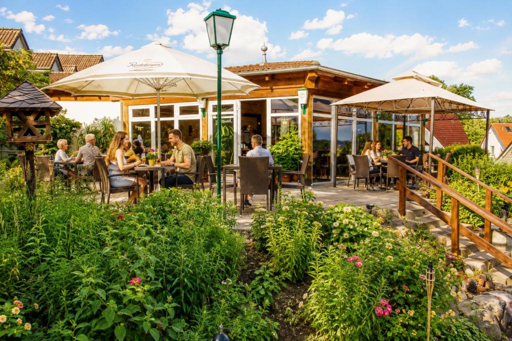 a patio with people sitting at tables in a garden at Landhotel Peters - zwischen zwei Seen in Canow