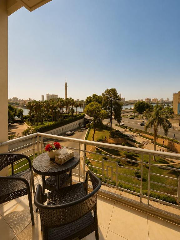 a balcony with a table and chairs and a view of a city at Garden Hotel Nile House in Cairo