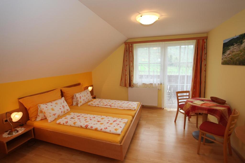 a bedroom with a bed and a desk and a window at Gästehaus Weinbergblick in Spitz