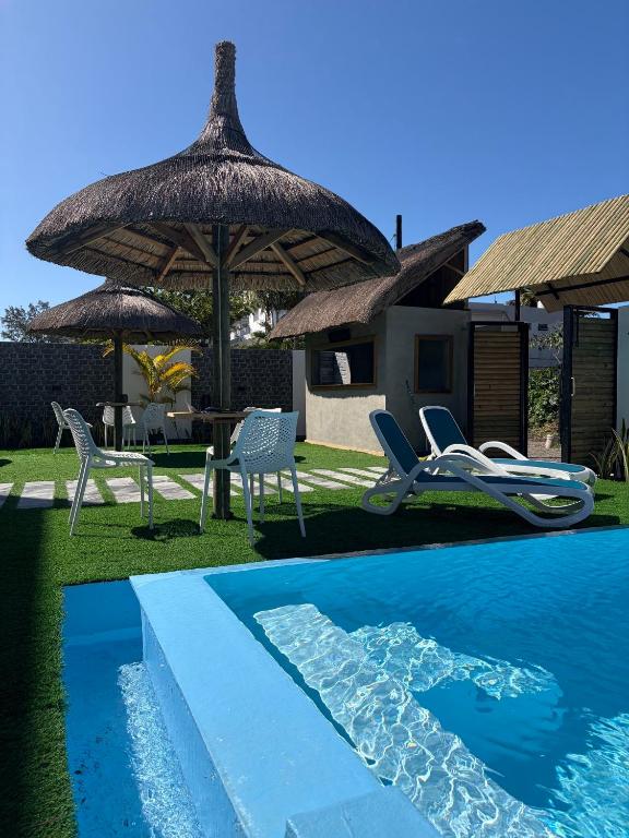 a resort with a pool and chairs and a umbrella at Appartement Zen VIP Péreybère in Grand-Baie