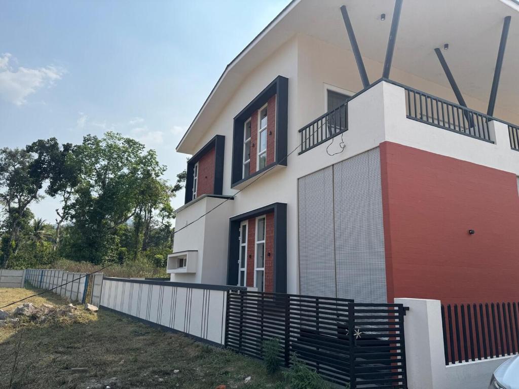 a white and red house with a fence around it at Coorg Family Villa in Gonikoppal