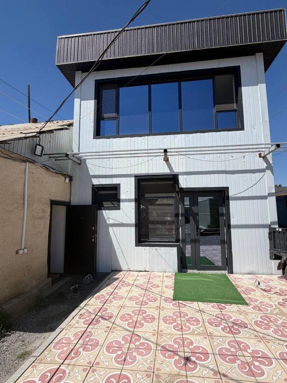 a white house with a green mat in front of it at Naryn Guest House in Naryn