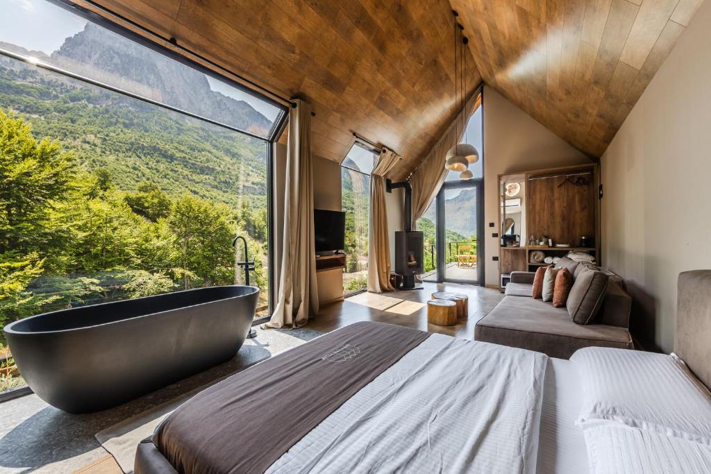a bedroom with a large window and a bath tub at North Alpine Villas in Bogë