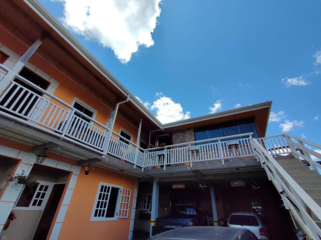 a house with a balcony and a car parked in front at SkyBlue Guesthouse by Concavus in Campos do Jordão