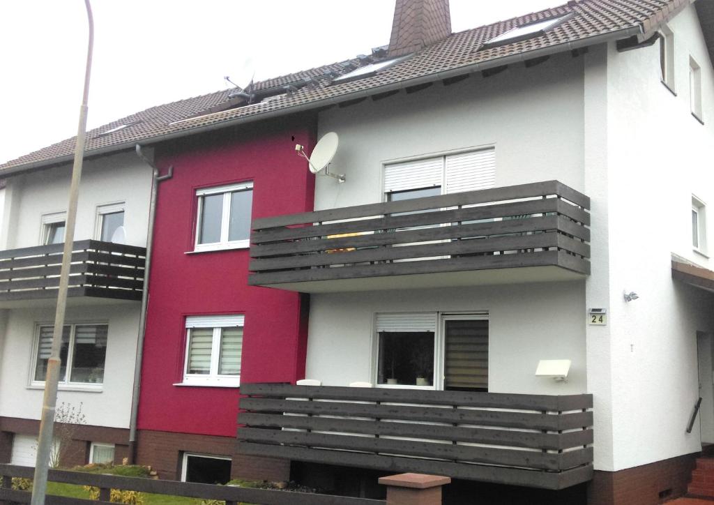 a red and white house with a balcony at Ferienwohnung Familie Perl in Immenhausen