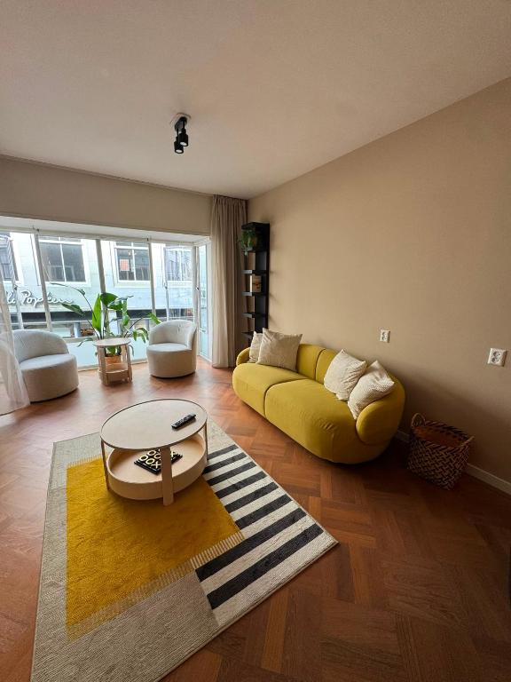 a living room with a yellow couch and a table at Appartement Moustache in Goes