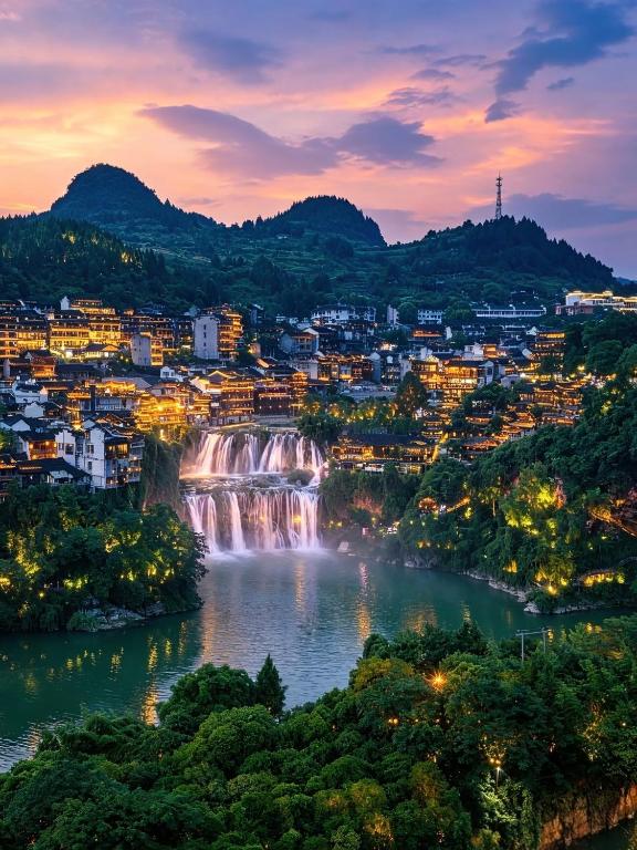a view of a waterfall and a city at night at Zhangjiajie Gui Yuan Hotel - Free delivery to the East Gate once--service washing machine with drying, luggage storage-over 4 nights and get one free airport pick-up in Zhangjiajie
