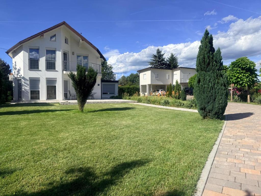 a large white house with a grass yard at Villa Amela in Ilidža