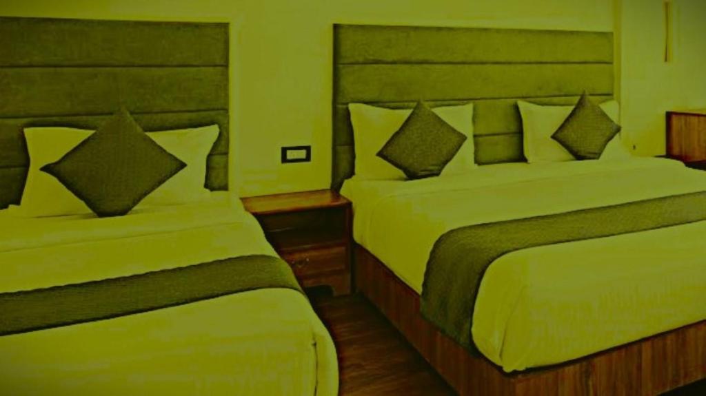 a bedroom with two beds with green sheets at The Nagpal Hotel in Haridwār