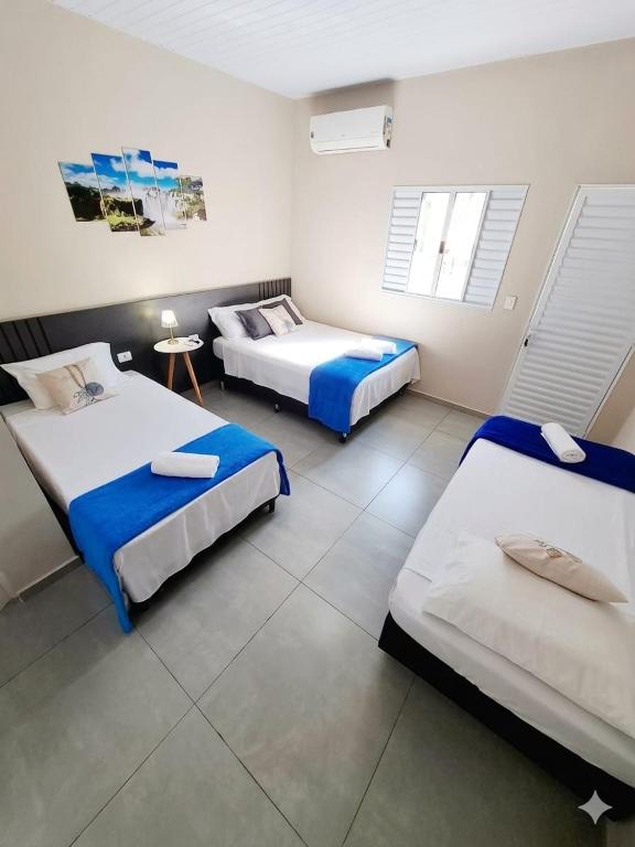 a room with three beds and a table in it at Studio Cataratas com garagem e ar condicionado in Foz do Iguaçu