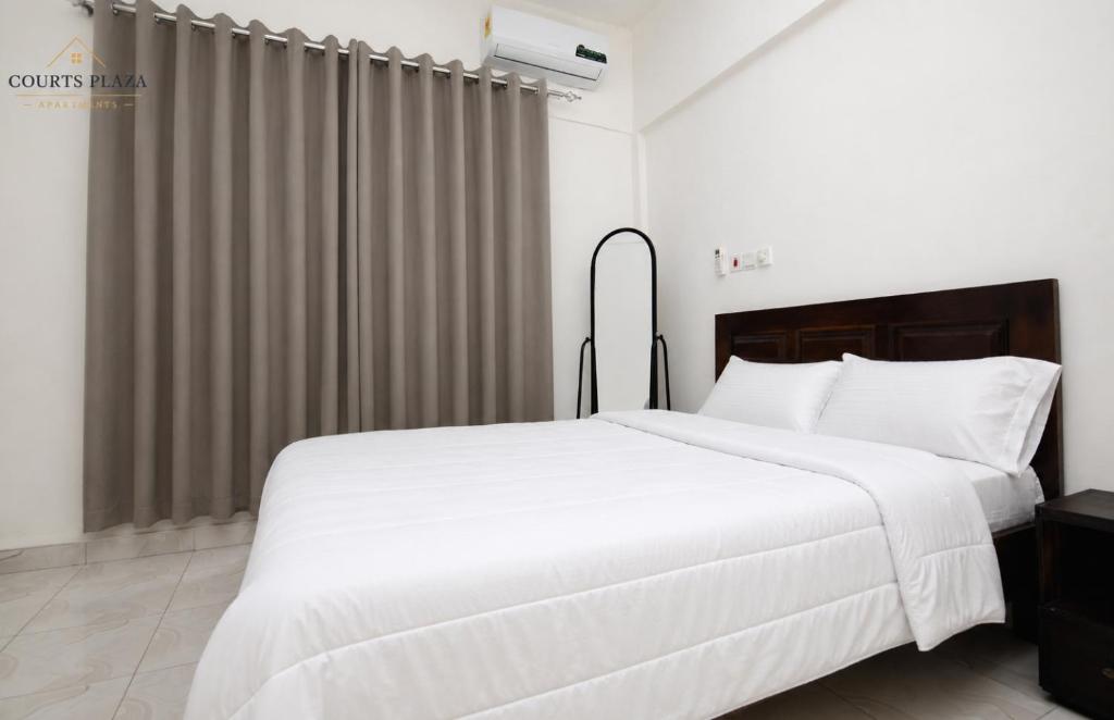 a bedroom with a large white bed and a window at Courts Plaza Apartments in Bawaleshi
